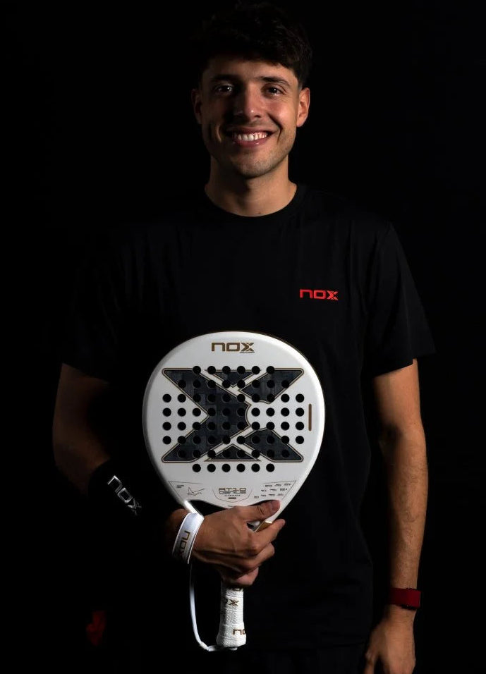 Person holding a NOX padel against a dark background